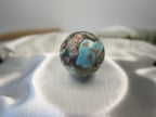 Treasured Energies polished Larimar sphere with blue and brown patterns resting on a soft white satin fabric