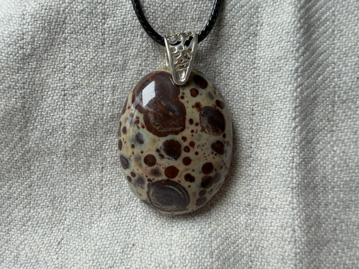 Treasured Energies polished poppy Jasper oval pendant with brown and cream spots on a black cord necklace
