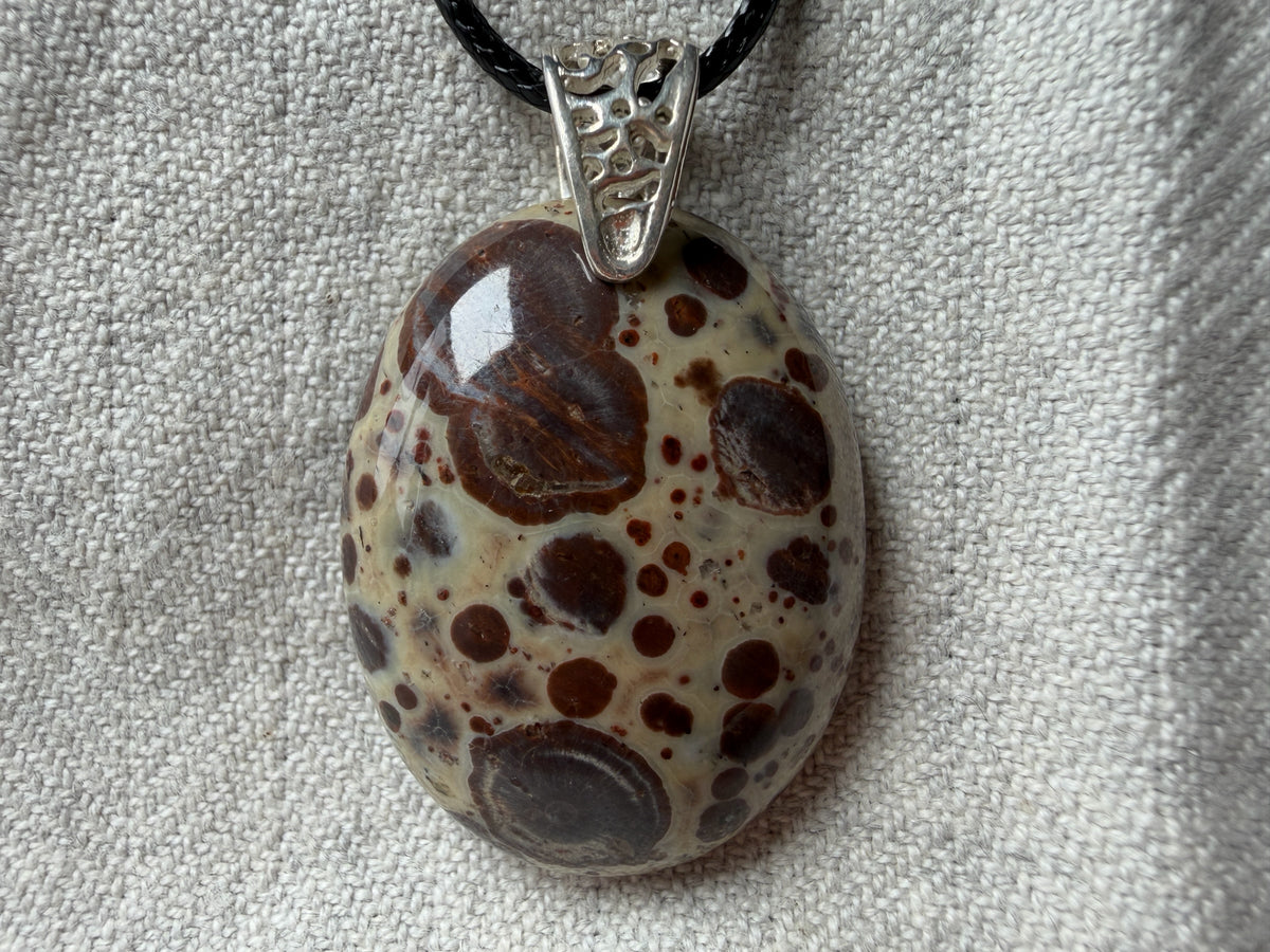 Treasured Energies polished oval poppy Jasper pendant with brown and cream spots on a black cord necklace