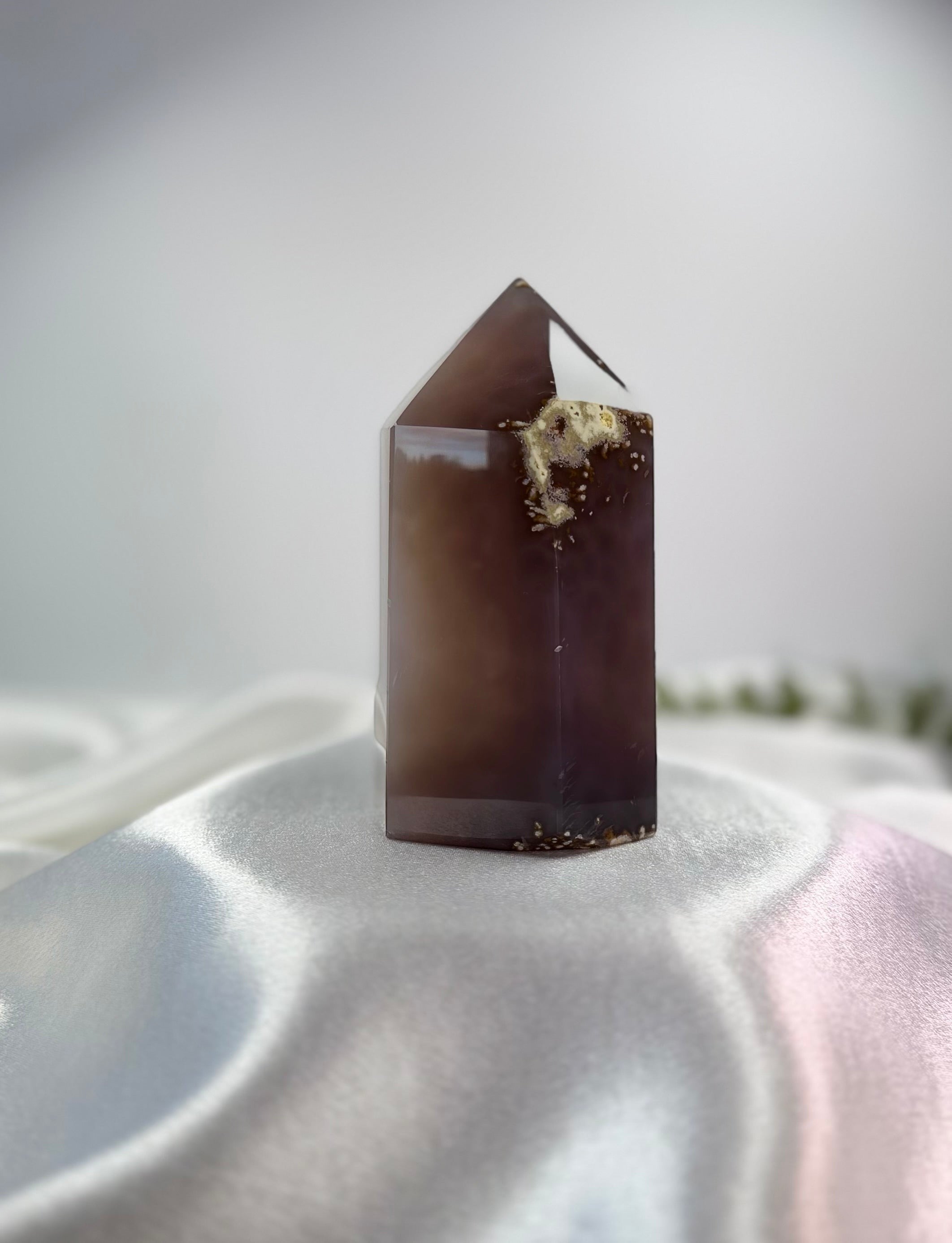 Treasured Energies polished lilac and grey agate crystal tower point with a sparkling druzy cluster on a white fabric.