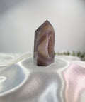Treasured Energies polished lilac and grey agate crystal tower with a sparkling druzy geode center on white silk.