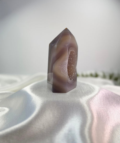 Treasured Energies polished lilac and grey agate crystal tower with a sparkling druzy geode center on white silk.