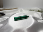 Treasured Energies polished malachite crystal tower with deep green banding resting on white satin fabric.