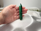 Treasured Energies polished malachite crystal tower held in a hand, showing vivid green banding and pointed tip.