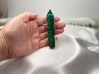 Treasured Energies polished malachite crystal tower held in a hand, showing vivid green banding and natural patterns.