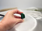 Treasured Energies high grade polished malachite tumbled stone with deep green banding held in a hand