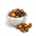 Treasured Energies Mookaite jasper tumbled stones in a white marble bowl with earthy red and yellow tones.