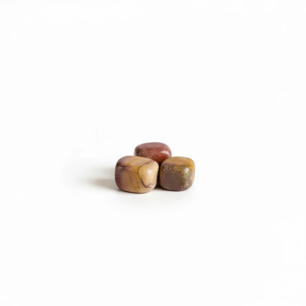 Treasured Energies Mookaite Jasper tumbled stones in earthy red, burgundy, and yellow hues on a white background.