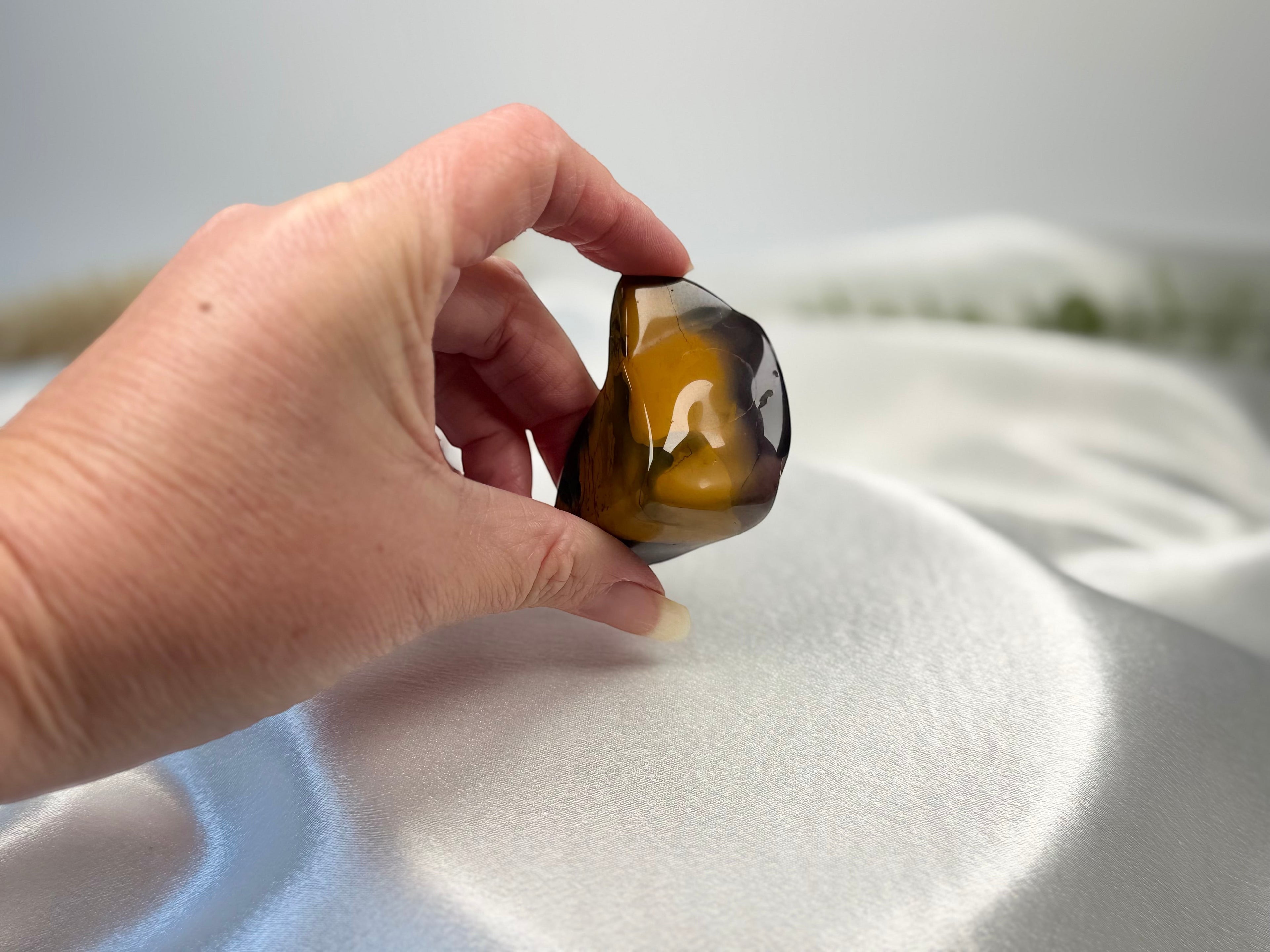 Treasured Energies high grade Mookaite tumbled stone with yellow and burgundy tones held in a hand.