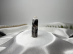 Treasured Energies moonstone crystal tower with black and white patterns standing on a draped white satin fabric.