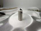 Treasured Energies moonstone crystal tower with black inclusions on a white satin background