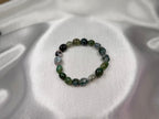 Treasured Energies moss agate crystal bead bracelet with natural green and white stone patterns on white satin