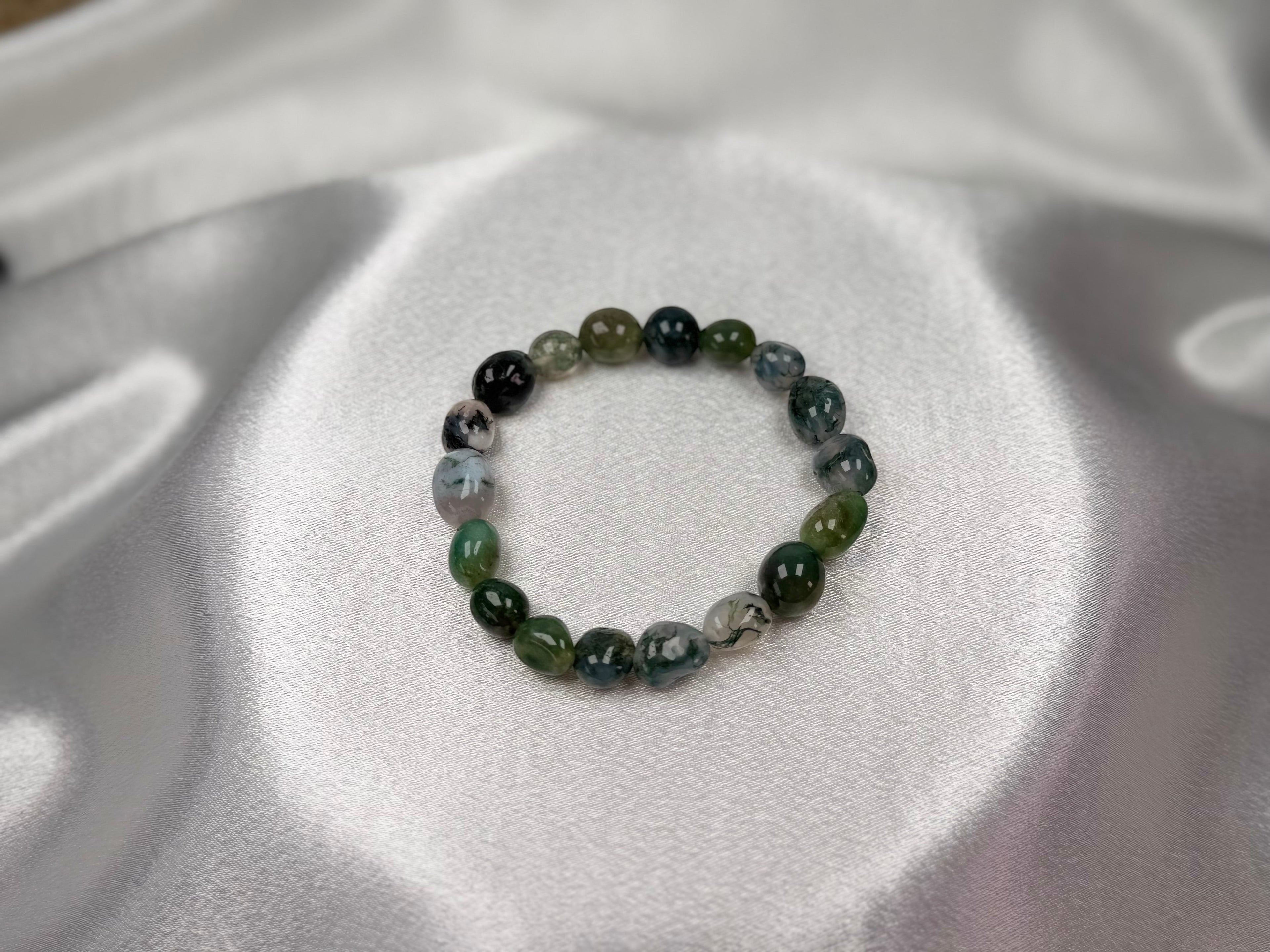 Treasured Energies moss agate crystal bead bracelet with natural green and white stone patterns on white satin