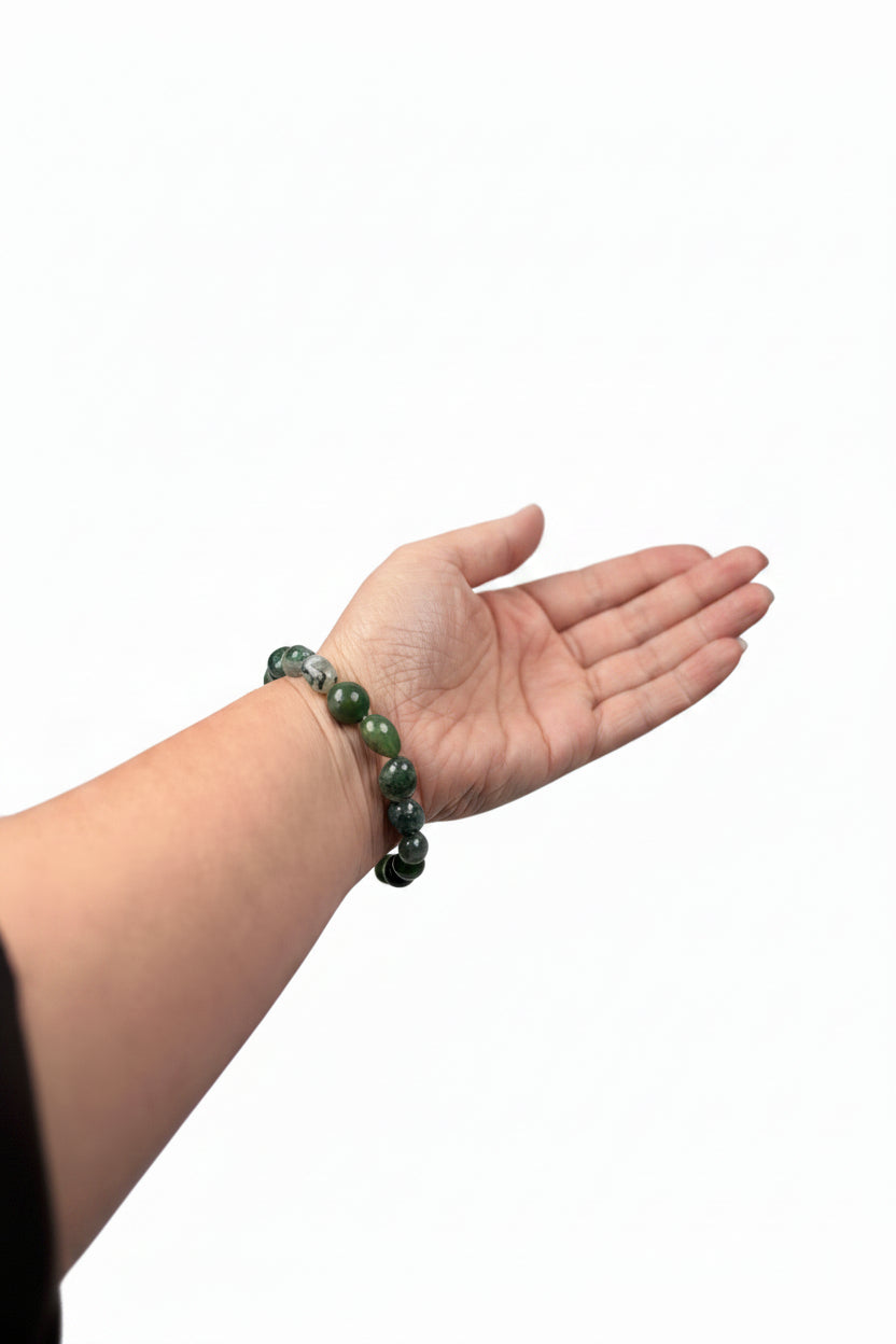 Treasured Energies moss agate crystal bead bracelet worn on a wrist while holding a small decorative hedgehog figurine