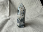 Treasured Energies polished Moss Agate crystal tower with green and white forest-like inclusions on a linen background
