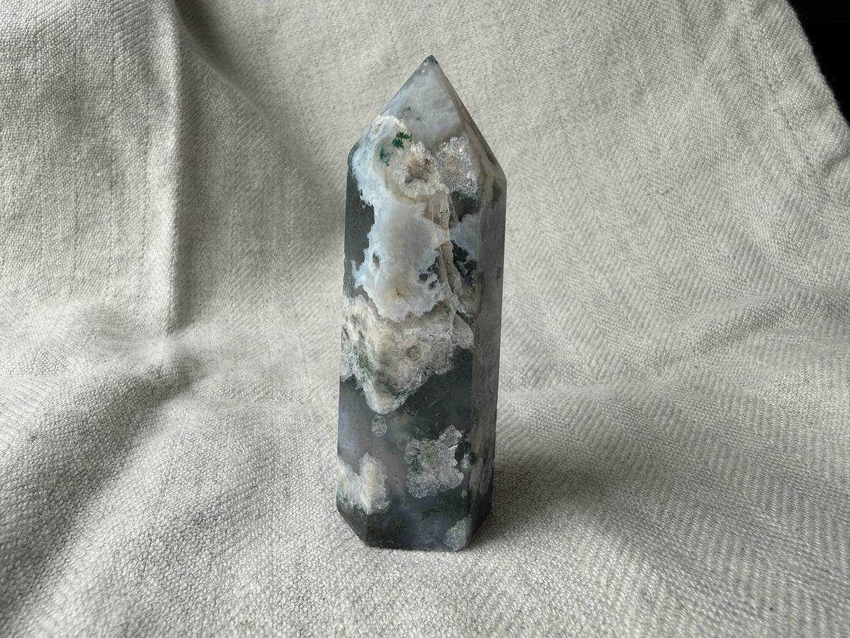 Treasured Energies polished Moss Agate crystal tower with green and white forest-like inclusions on a linen background