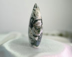 Treasured Energies polished moss agate flame crystal sculpture with green and white mineral patterns on a white cloth.
