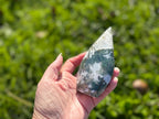 Treasured Energies hand-polished moss agate freeform crystal with green and white inclusions held outdoors