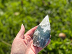 Treasured Energies hand-polished moss agate freeform crystal with green and white earthy inclusions held in a hand