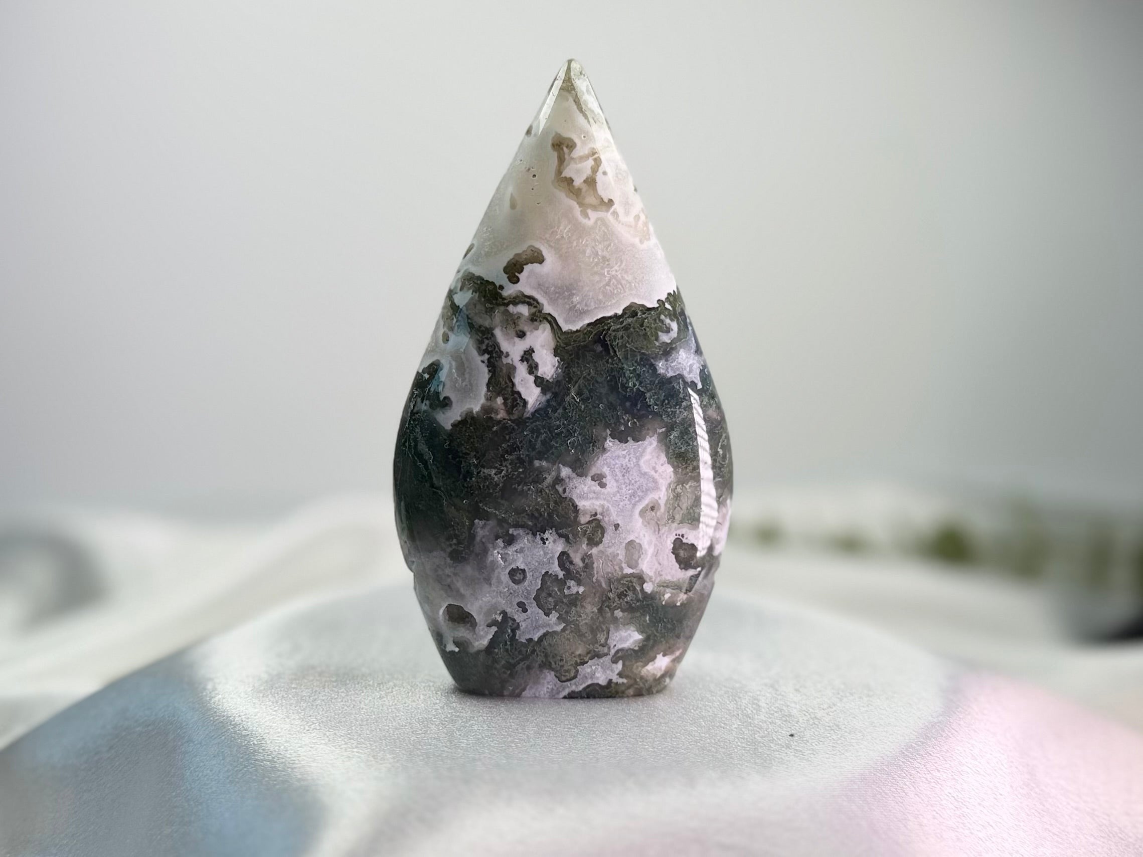 Treasured Energies polished moss agate freeform crystal with organic green and white mineral patterns on a white cloth