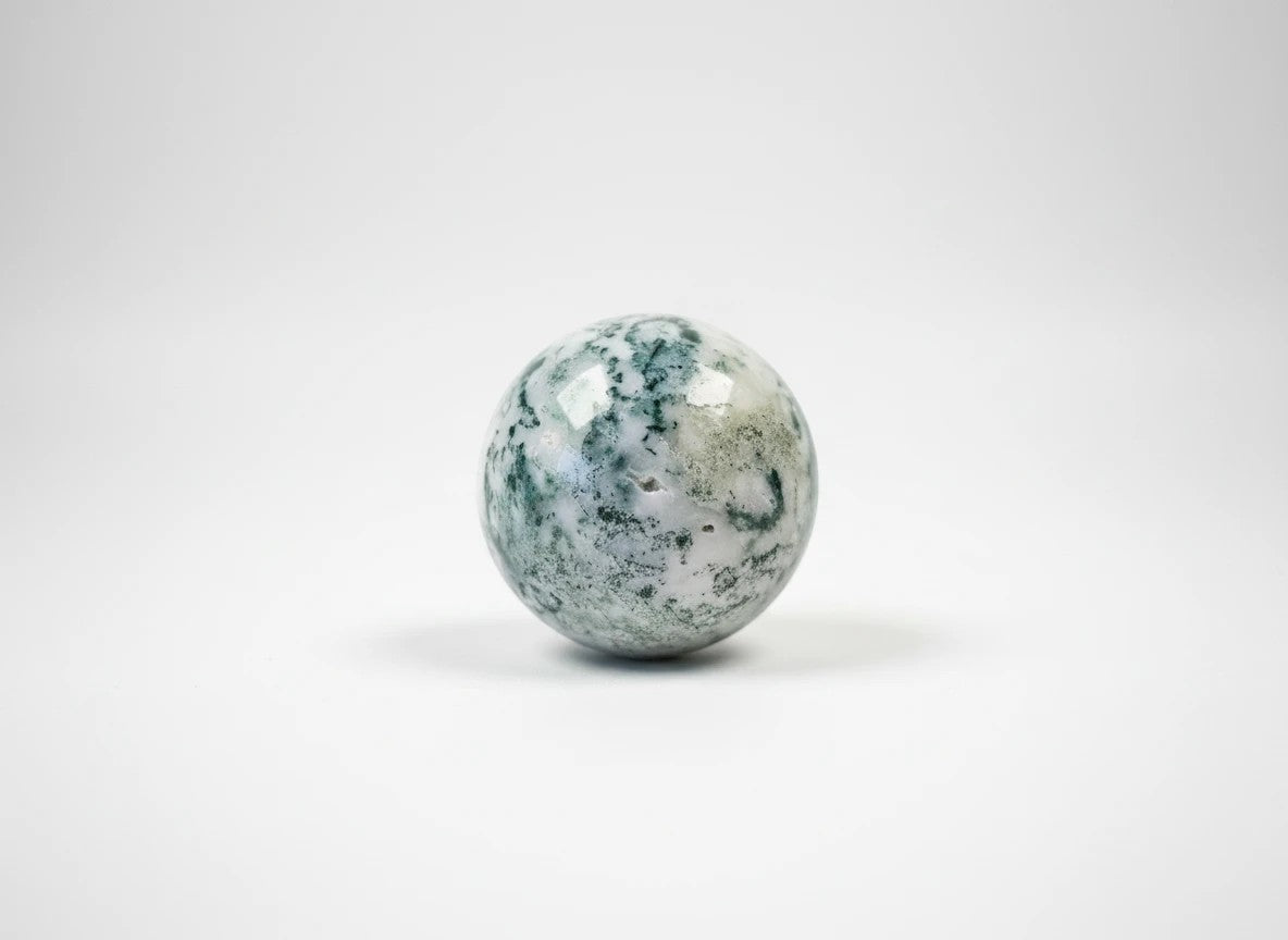 Treasured Energies polished moss agate crystal sphere with green moss-like inclusions on a white background