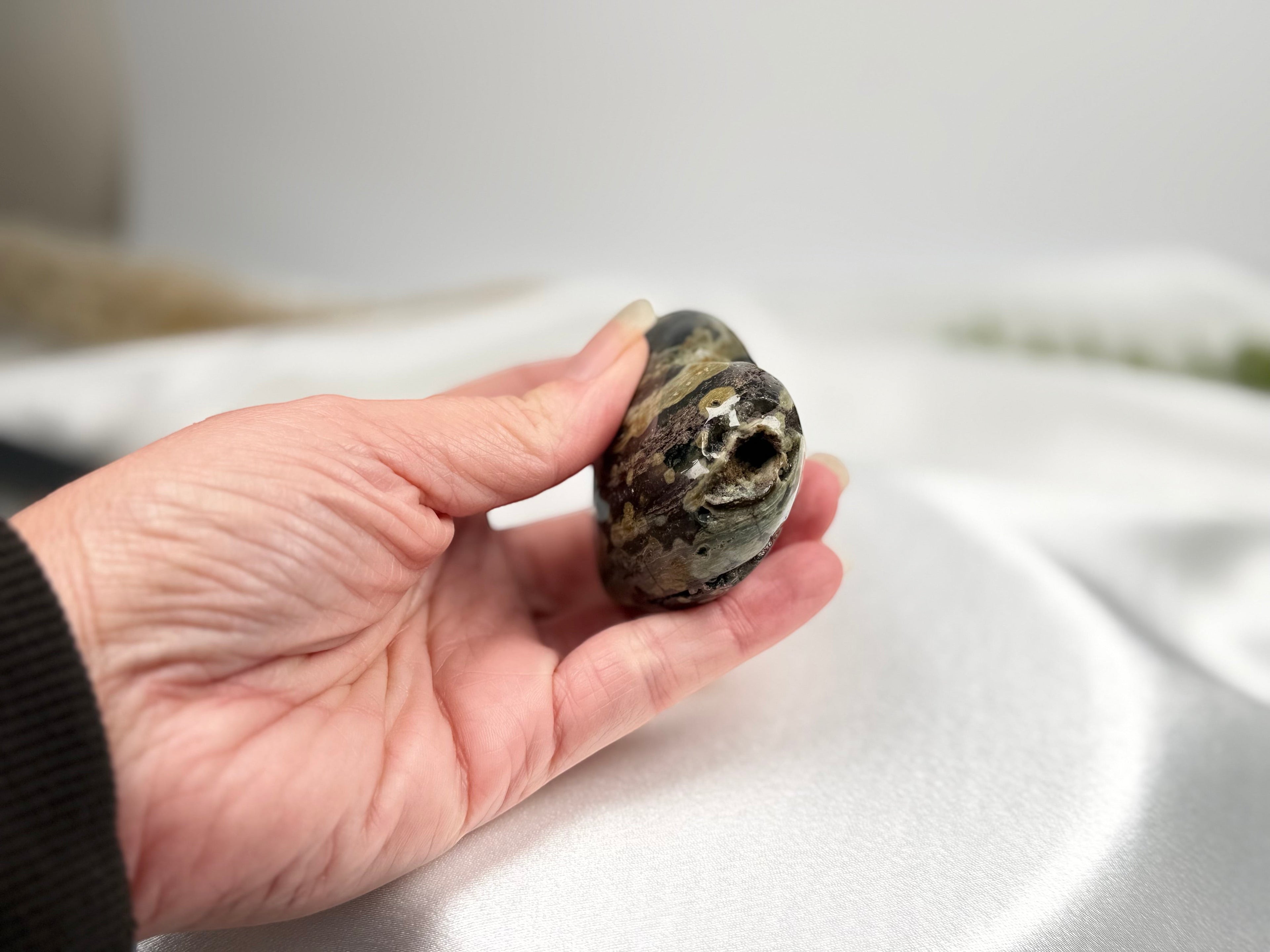 Treasured Energies large heart-shaped Ocean Jasper crystal held in a hand, showing natural green and brown patterns.