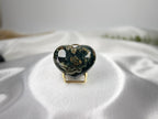 Treasured Energies large heart-shaped Ocean Jasper crystal with dark green and earthy patterns on a white silk cloth.