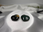Two Treasured Energies small heart-shaped Ocean Jasper crystals with dark green and gold patterns on white silk.