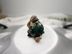 Treasured Energies small polished green Ocean Jasper heart held by a cute carved platypus figurine on white fabric
