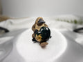Treasured Energies small heart-shaped Ocean Jasper crystal held by a decorative platypus figurine on a white surface.