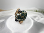Treasured Energies large polished Ocean Jasper crystal heart with green and brown orbicular patterns held by a figurine