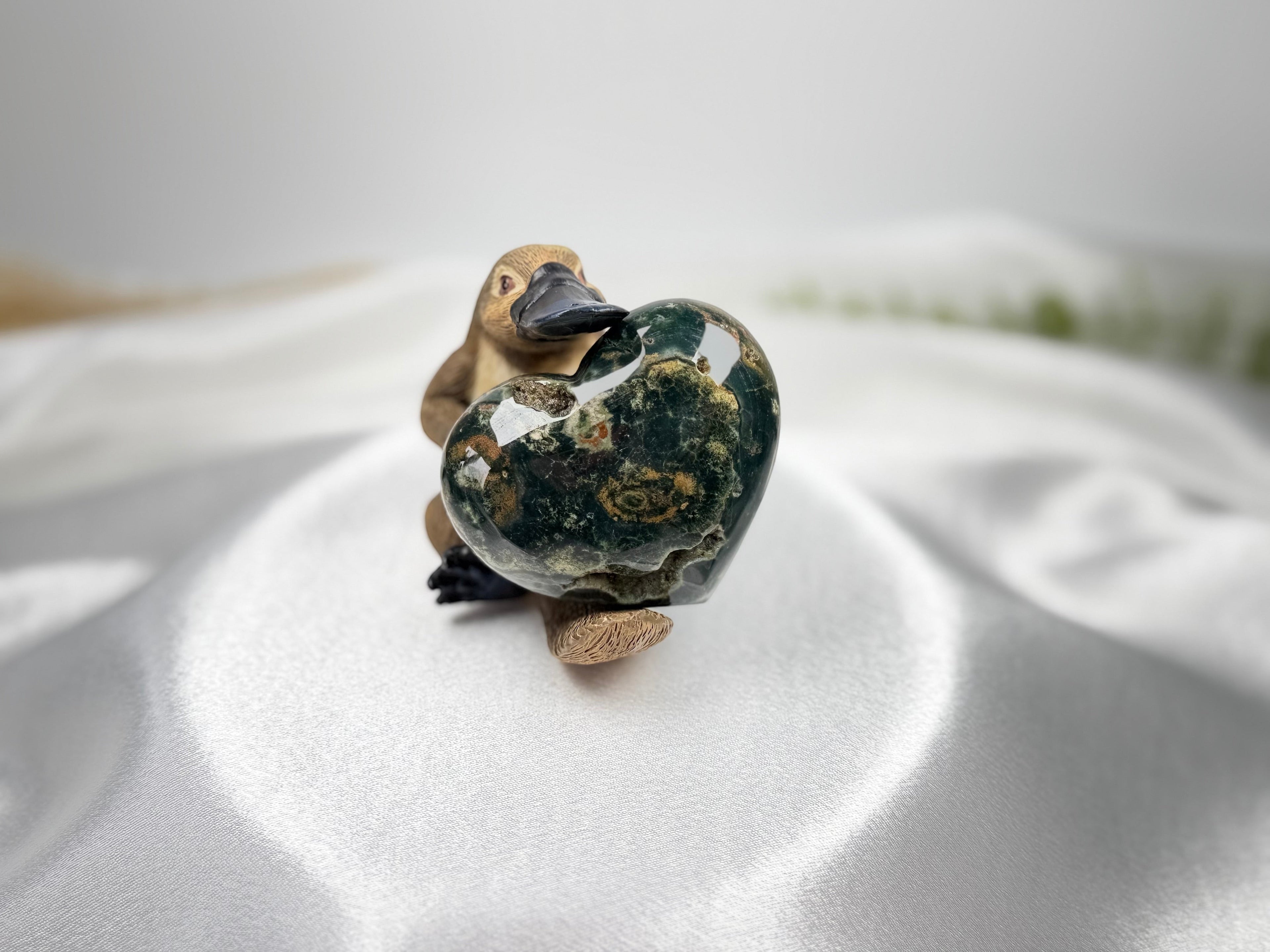 Treasured Energies large polished Ocean Jasper crystal heart with green and brown orbicular patterns held by a figurine