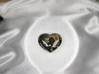 Treasured Energies large polished Ocean Jasper crystal heart with dark green and brown patterns on white satin fabric.