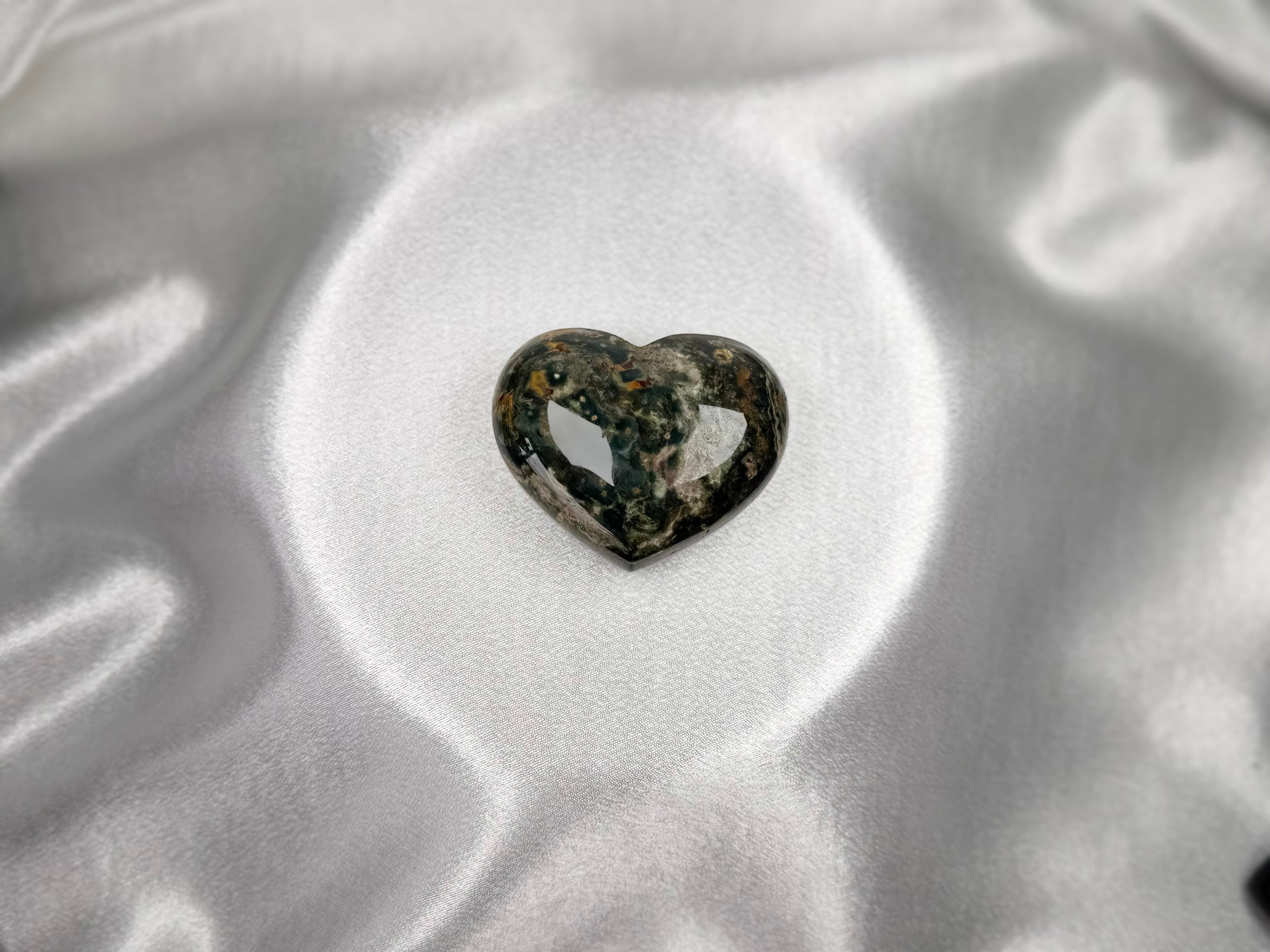 Treasured Energies large polished Ocean Jasper crystal heart with dark green and brown patterns on white satin.
