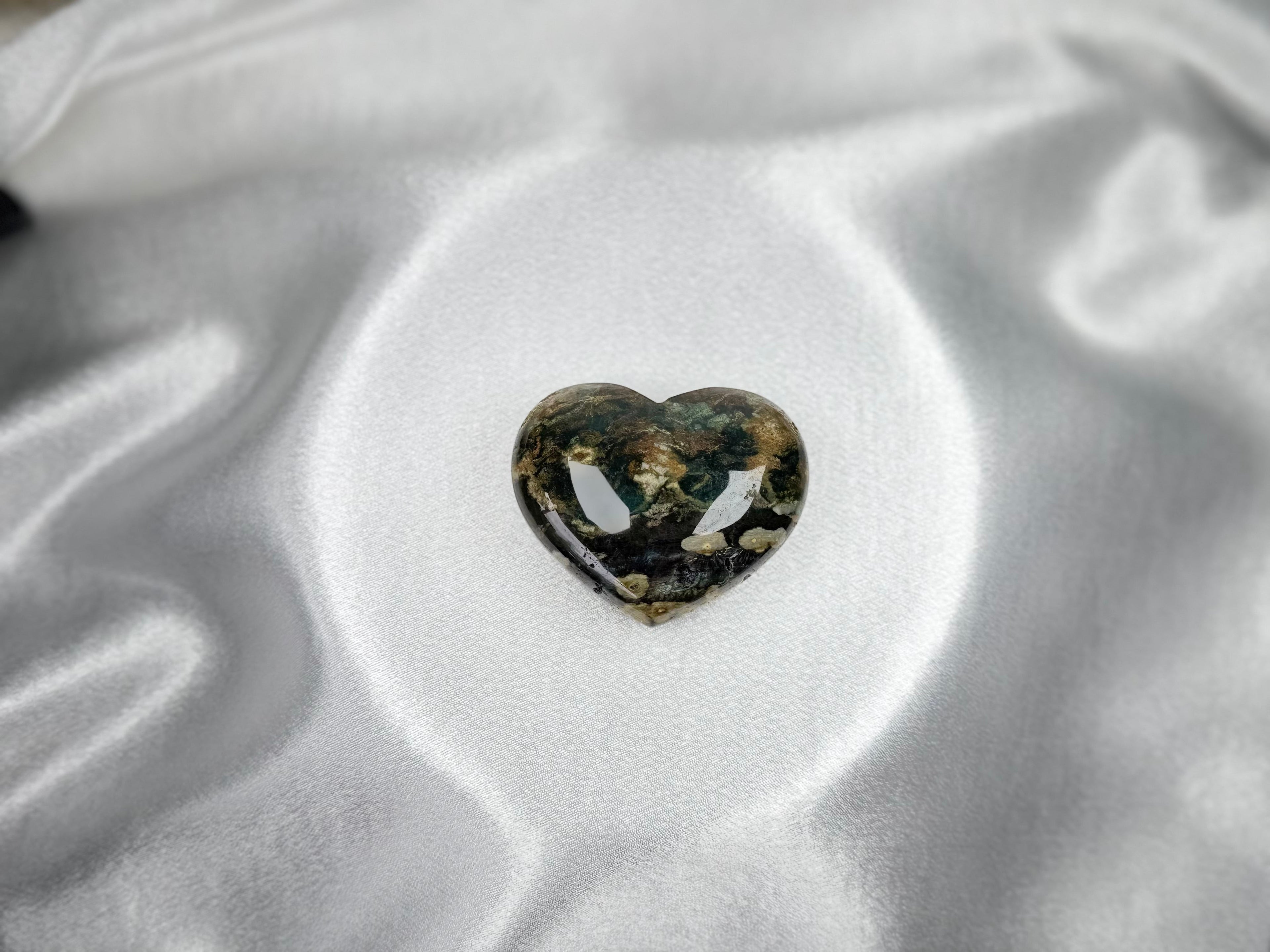 Treasured Energies large polished Ocean Jasper crystal heart with green and cream patterns on white satin fabric