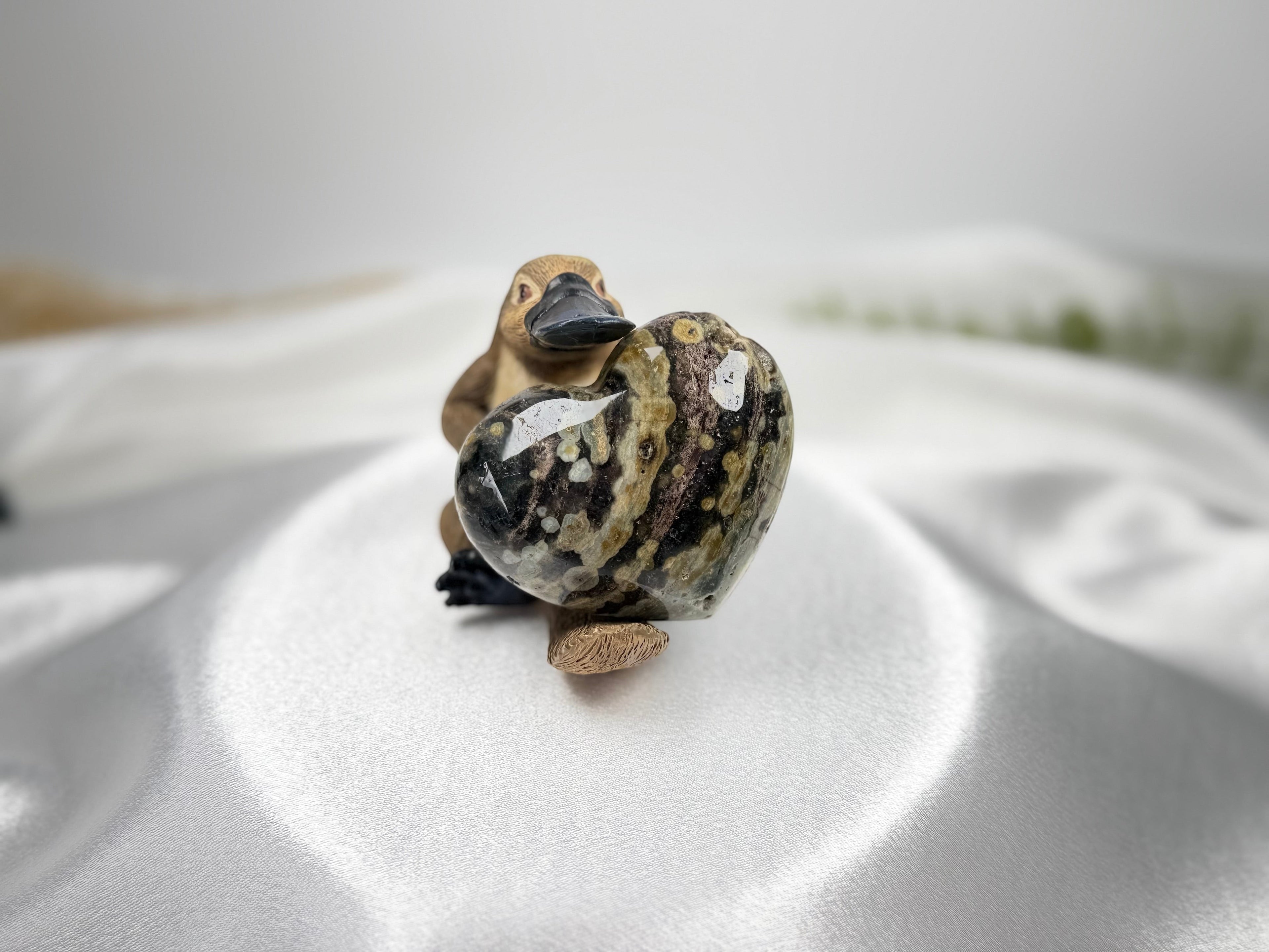 Treasured Energies large polished heart-shaped Ocean Jasper crystal with unique orbicular patterns held by a figurine
