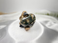 Treasured Energies large polished Ocean Jasper crystal heart held by a small platypus figurine on white satin fabric.