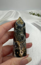 Treasured Energies Ocean Jasper crystal tower with dark green, brown, and cream orbicular patterns held in a hand.