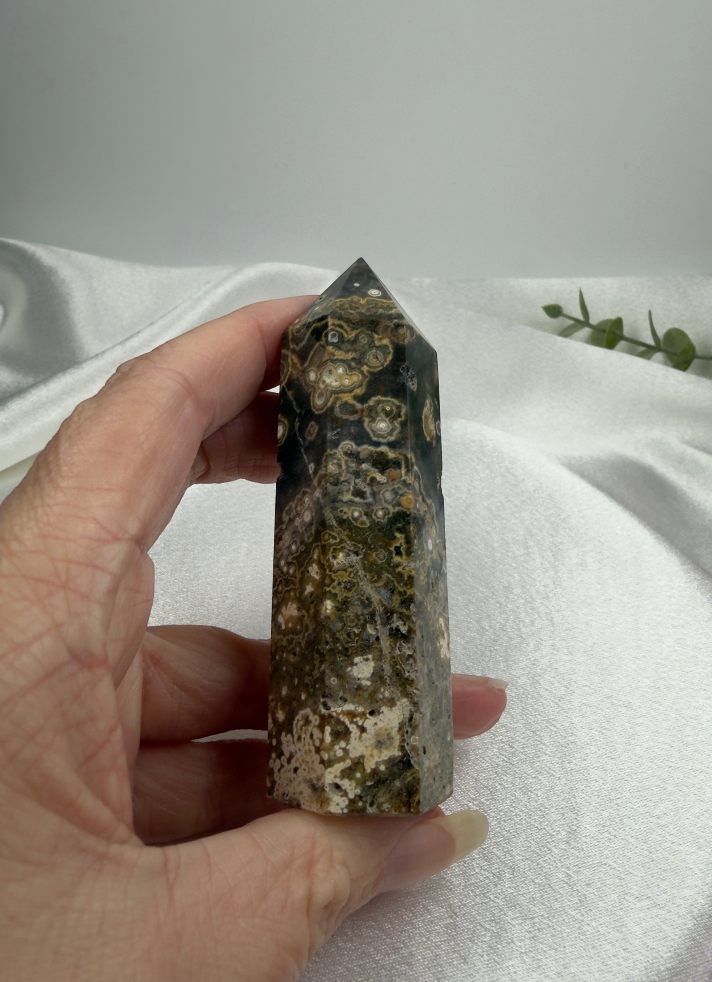Treasured Energies Ocean Jasper crystal tower held in hand, featuring dark green, brown, and cream orbicular patterns.