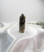 Treasured Energies Ocean Jasper crystal tower with dark brown and cream orbicular patterns on a white silk fabric.