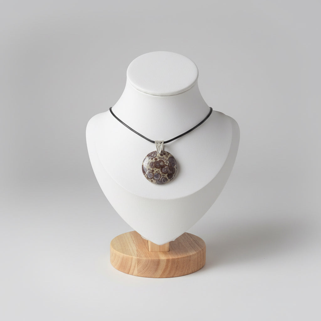 Treasured Energies polished orbicular poppy jasper pendant with brown tan spots on a black cord displayed on a white bust