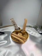 Treasured Energies palo santo sticks and white sage bundle in a small brown ceramic holder on white satin fabric