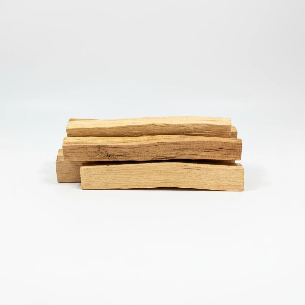 Treasured Energies palo santo sticks stacked on a white background for smudging and aromatherapy