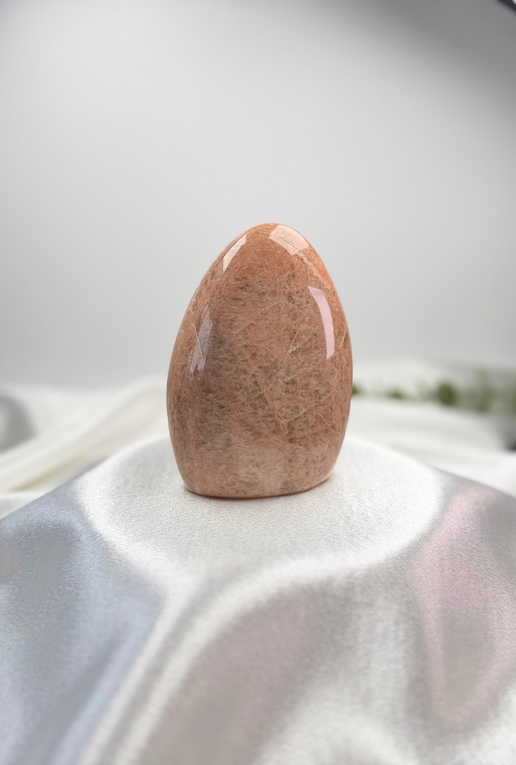 Treasured Energies polished peach moonstone crystal freeform with smooth surface and organic shape on white fabric
