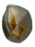 Treasured Energies agate crystal point with polished facets, showing natural grey and amber banding on white background.