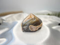 Treasured Energies polished agate point with natural grey and brown banding on a white satin background