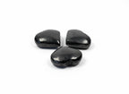 Three polished black shungite heart stones from Treasured Energies arranged on a white background.