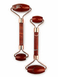 Treasured Energies dual-ended red jasper facial massage rollers with rose gold hardware on a white background.