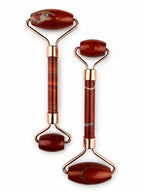 Treasured Energies dual-ended red jasper facial massage rollers with rose gold hardware on a white background.