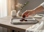 Treasured Energies red tiger's eye worry stones on a marble tray with a hand holding one, set on a desk with a diffuser.